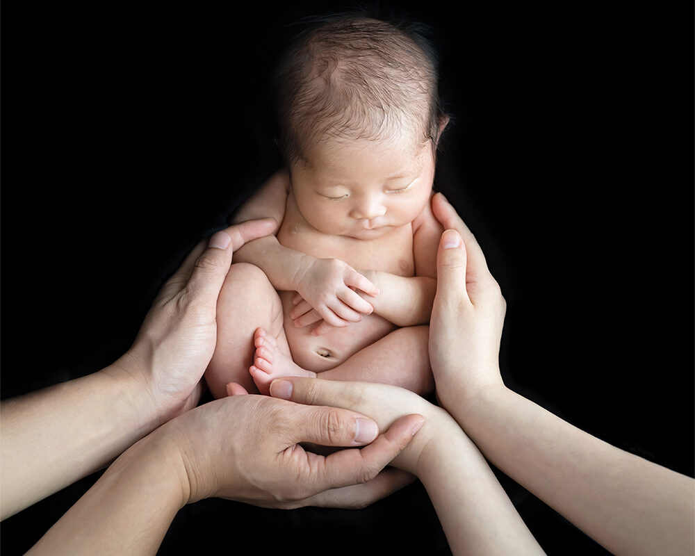パパとママの手に包まれる赤ちゃんのニューボーンフォト（豊中市のふみる）