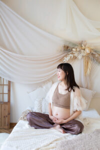 お腹に手を添える妊婦さんを柔らかい光で撮影したマタニティフォト_吹田・豊中フォトスタジオ