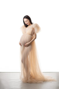 お腹に手を添える妊婦さんを柔らかい光で撮影したマタニティフォト_美しいドレス_吹田市のフォトスタジオふみる｜レンタルドレス